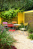 Sitzplatz vor gelb gestrichener Mauer mit Rankgerüst (Appeltern, Niederlande)