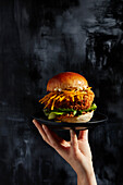 Portabello-Burger auf Teller, der von einer Hand gehalten wird