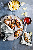 Grilled chicken legs with ketchup and potato chips