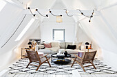 Dachgeschoss-Wohnzimmer mit Rattansesseln, heller Couch und gemustertem Teppich