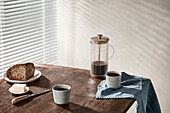 Frühstück mit Kaffee und Butterbrot auf Holztisch