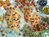 Foccaccia with yellow and red tomatoes, olives, oregano, rosemary, and olive oil