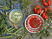 Tomato soup and pea soup, surrounded by fresh ingredients