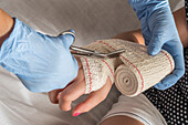 Nurse tying bandage on patient's foot