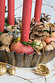 Backform gefüllt mit Kerzen in Äpfel gesteckt, vergoldete Walnüsse und Eicheln