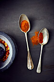 Paprika spice on two spoons and chilli flakes in a mortar