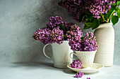 Lila Fliedersträuße in Tassen und Vasen