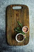 Himalayan salt, rosemary and coloured peppercorns on a wooden board