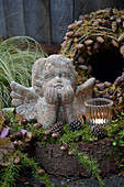 Angel garden sculpture next to a tea light on a tree stump