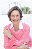 Frau in pinkfarbenem Pullover und weißem Hemd am Strand