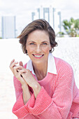 Frau in pinkfarbenem Pullover und weißem Hemd am Strand