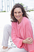 Frau in pinkfarbenem Pullover und weißer Hose