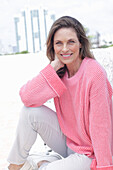 Frau in pinkfarbenem Pullover und weißer Hose