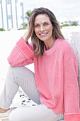 Frau in pinkfarbenem Pullover und weißer Hose