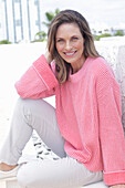 Frau in pinkfarbenem Pullover und weißer Hose