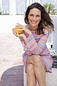 Long-haired woman with an orange in a short crochet dress