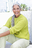 Gray-haired woman in a green-yellow knit sweater and light-colored trousers