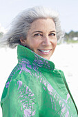 A grey-haired woman wearing a green coat