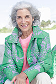 Grauhaarige Frau in grünem Mantel