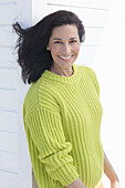 A mature, dark-haired woman wearing a greenish-yellow knitted sweater