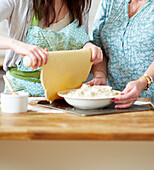 Two women preparing a lemony chicken pot pie
