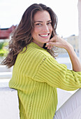 A long-haired woman wearing a green-yellow knitted jumper