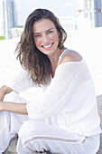 Happy long haired woman in white jumper and white trousers