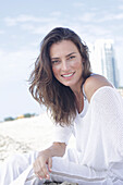 A long-haired woman wearing a white jumper and white trousers