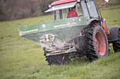 Farmer spreading artificial fertiliser on grass field