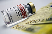 Covid-19 vaccine next to euro banknotes, concept image