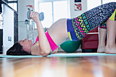 Pregnant woman exercising at home with dumbbells
