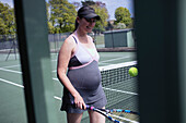 Pregnant woman in dress playing tennis
