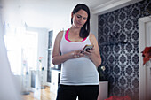 Pregnant woman in tank top using smart phone