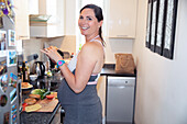 Smiling pregnant woman eating sandwich in kitchen
