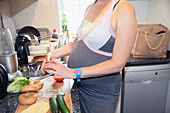 Pregnant woman making sandwich in kitchen