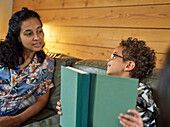 Mother talking to son with book on sofa