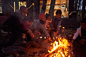 Family toasting marshmallows at campfire outside cabin