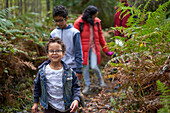 Portrait cute boy hiking with family on trail in woods