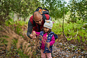 Father and curious toddler daughter hiking in woods