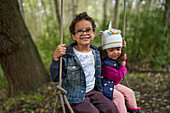 Brother and sister on swing in woods