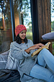 Woman relaxing and reading book on cabin patio