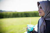 Young woman in headscarf drinking juice
