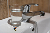 Glass of water and pills on bathroom sink