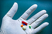 White gloved hand holding several pills