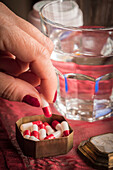 Woman taking a red and white pill from a pillbox