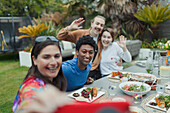 Happy couples taking selfie at patio lunch table