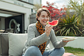 Happy woman eating watermelon on summer patio