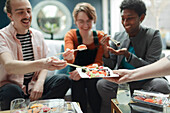 Happy friends sharing takeout sushi in living room