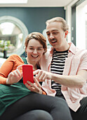 Happy couple with smart phone at home
