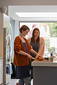 Women friends slicing loaf cake in kitchen